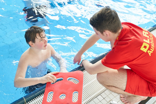 Ein DLRG-Ausbilder erklärt einem Jugendlichen die Schwimmübung.